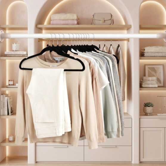 Slim velvet hangers holding neutral sweaters and pants in an organized closet